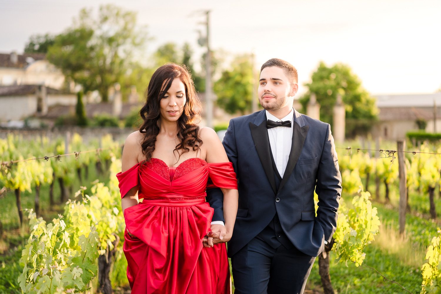 Safia et Antoine marchent main dans la main dans les vignes, capturés par Michael Jamet, photographe de mariage dans les Landes